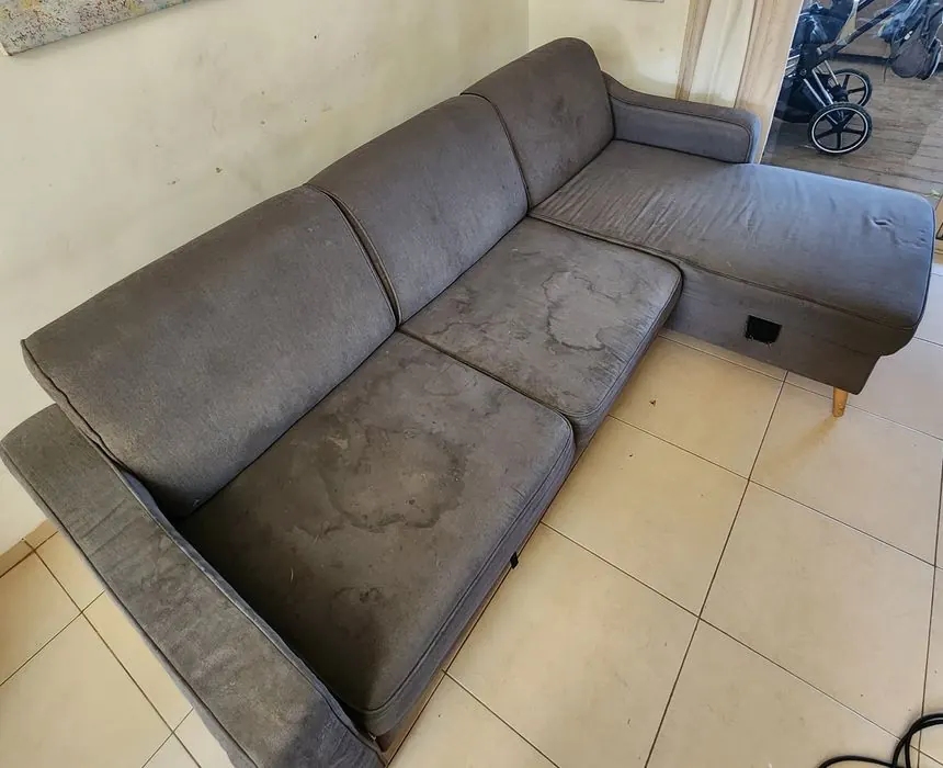 ספה אפורה עם שזלונג וכתמי מים גדולים לפני ניקוי
